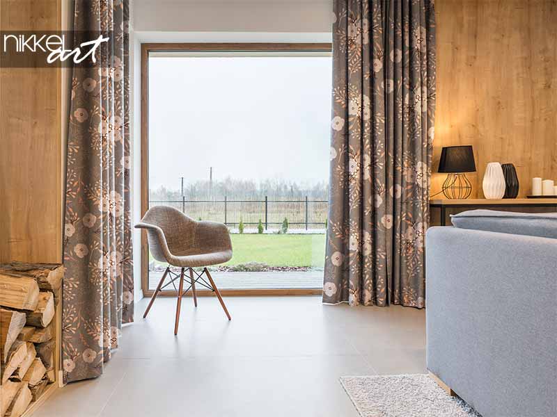 Rideaux taupe à motif floral devant un mur en bois et un canapé gris
